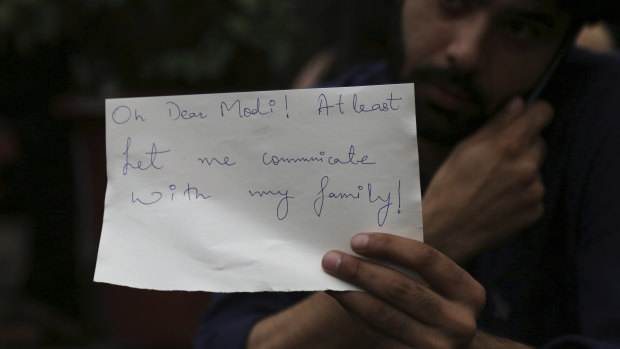 A Kashmiri, who works in Bangalore, holds a piece of paper addressing Indian Prime Minister Narendra Modi during a protest in Bangalore.