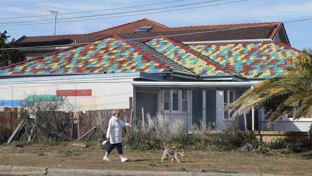 A woman walks her dog past the home. John Hall painted each tile in one of four colours in the stunning tribute.