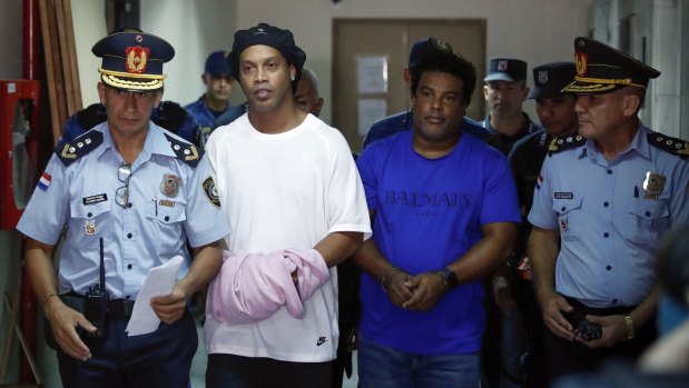 Former soccer star Ronaldinho, second from left, and his brother Roberto de Assis Moreira walks escorted by police officers to declare to judge Clara Ruiz Diaz at Justice Palace in Asuncion, Paraguay. 
