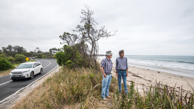 Locals Dave Sutton (left) and Phillip Heath on the remaining strip separating the surf beach from the road at Inverloch, where erosion has caused major problems.