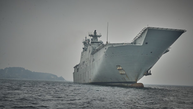 HMAS Adelaide waits to help off the coast of Eden on Wednesday.