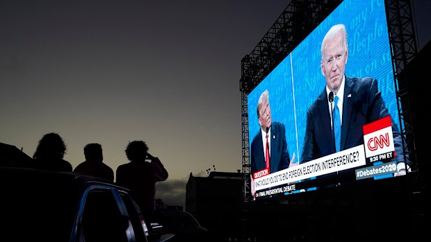 People watch from their vehicle as President Donald Trump, on left of video screen, and Democratic presidential candidate former Vice President Joe Biden speak during a Presidential Debate Watch Party at Fort Mason Center in San Francisco