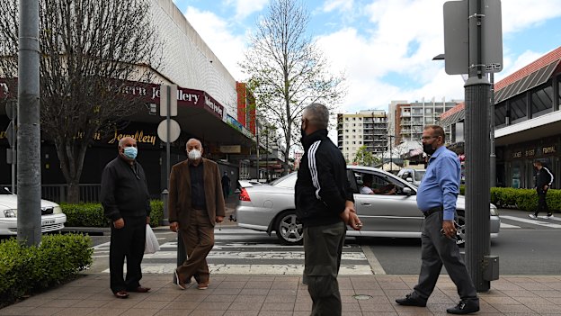 A group of elderly men greet each other from a distance at the Fairfield shopping strip.