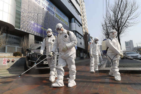 Workers wearing protective gears spray disinfectant against the new coronavirus in front of a church in Daegu, South Korea, where dozens of cases are linked to one church. 