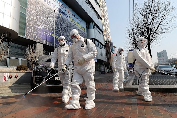 Workers wearing protective gears spray disinfectant against the new coronavirus in front of a church in Daegu, South Korea, where dozens of cases are linked to one church. 