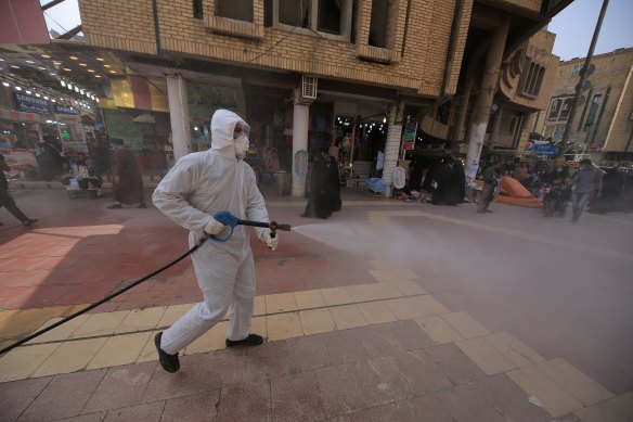 Iraqi health officials spray disinfectant as a precaution against the coronavirus in downtown Najaf, Iraq.