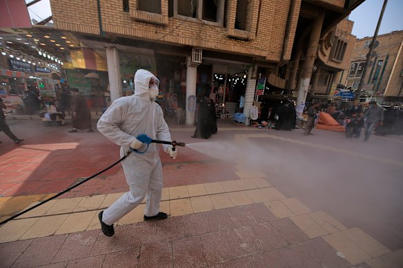 Iraqi health officials spray disinfectant as a precaution against the coronavirus in downtown Najaf, Iraq.