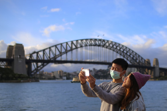 People wear face masks in front of the Sydney Harbour Bridge on Monday.