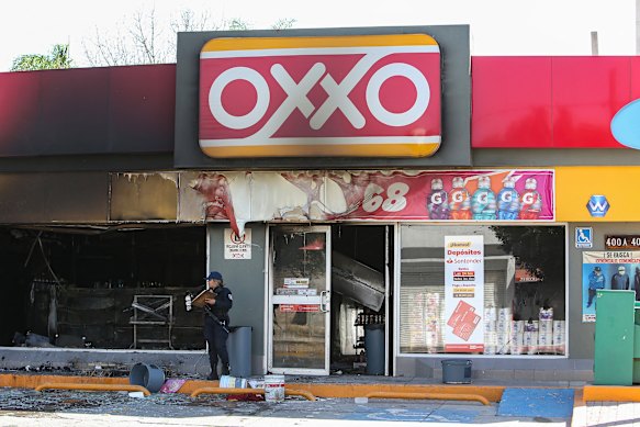 A Mexican state police officer inspects an Oxxo convenience store allegedly set on fire by members of the cartel.  