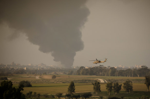  An Israeli helicopter flies a long the border as smoke is rising from the Gaza Strip .
