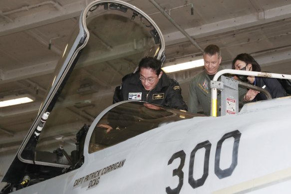 Fumio Kishida gets into the cockpit of a US fighter jet during his visit to the USS Ronald Reagan, in Sagami Bay, southwest of Tokyo on November 6, 2022. 