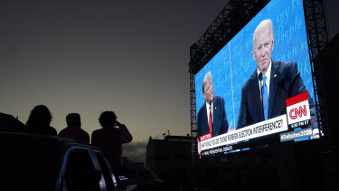People watch from their vehicle as President Donald Trump, on left of video screen, and Democratic presidential candidate former Vice President Joe Biden speak during a Presidential Debate Watch Party at Fort Mason Center in San Francisco