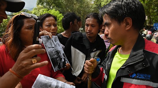 Dhan Bahadur Tamang (a destra), sopravvissuto alla valanga nel tunnel, parla con alcune donne disperate di sapere dove si trovi una persona cara scomparsa. 