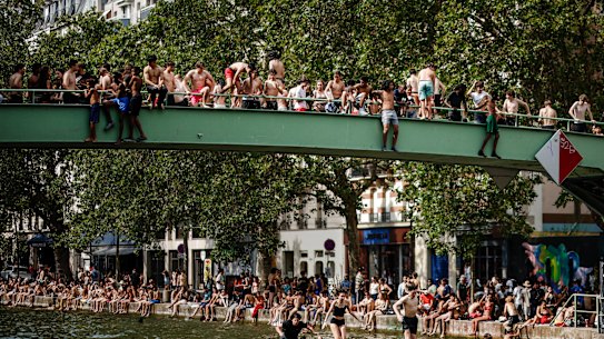 Young Parisians jump from a bridge to cool off in the Canal Saint-Martin in Paris.