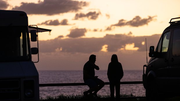 People gather by a coffee truck on the southern headland at Avalon Beach to watch the sunrise.