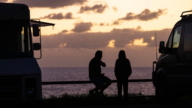 People gather by a coffee truck on the southern headland at Avalon Beach to watch the sunrise.