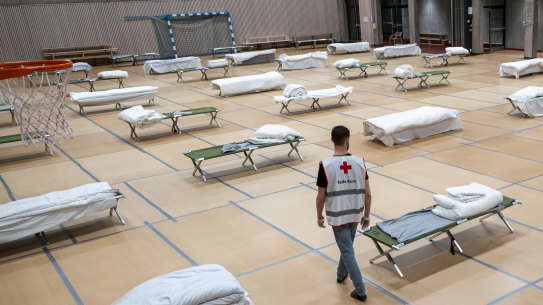 A Red Cross volunteer looks at beds set up for homeless people in the gymnasium of Uranienborg school, which is closed due to the corona eruption, in Oslo, Thursday, March 26, 2020. 