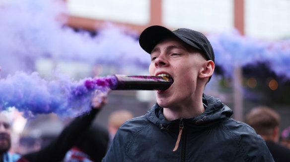 A fan holds a smoke flare in his mouth outside the stadium prior to the Premier League match between Aston Villa and Liverpool FC at Villa Park in Birmingham, England.