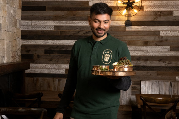 Munwar Hussain  at his IndoChainese restaurant holding a  Gongura chicken biryani. 