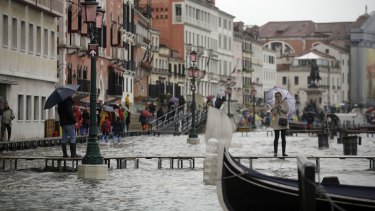 A woman stands on a temporary catwalk, right, to take pictures of Venice's second highest tide on record. 