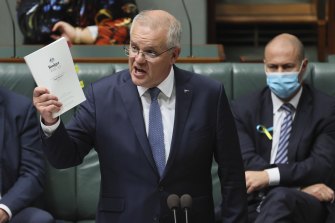 Scott Morrison holding up the budget papers in Parliament.
