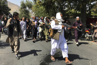 Armed Taliban soldiers walk towards Afghan protesters during the demonstration.