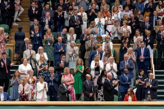 Los miembros de la familia real y los espectadores se paran frente a la profesora de Oxford Sarah Gilbert (sentada en rojo, abajo a la derecha) en el día inaugural de Wimbledon. 