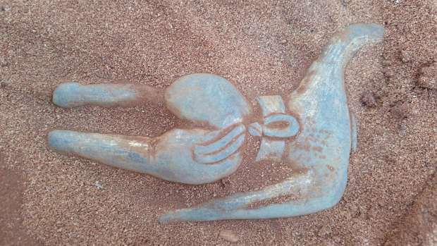 They brushed away the sand before gently dislodging the statue from its resting place. 