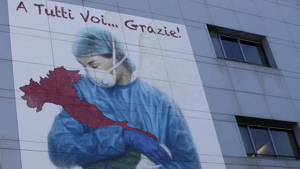 A giant image of a drawing by Venetian artist Franco Rivolli showing a doctor with wings on her back cradling Italy and writing in Italian reading "To all of you... Thank you!",