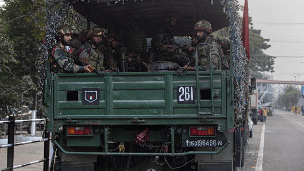 Indian army soldiers in a vehicle get ready for a flag march during a curfew in Gauhati, India.