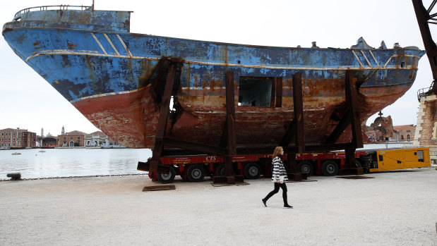 A woman walks past the wreck of the 'Barca Nostra' fishing boat, which sank in the Mediterranean Sea in 2015 with 700 migrants on board, at the 58th Venice Biennale.