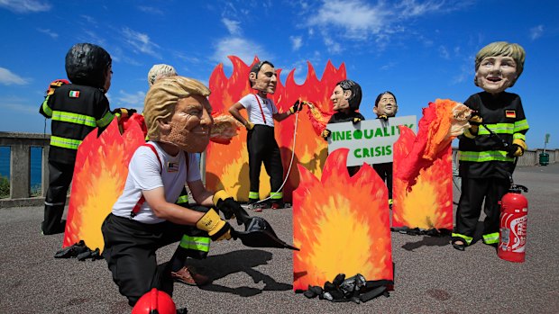 A man wearing a mask President Donald Trump, front left, is joined by other 'world leaders' during a protest ahead of the G-7 summit in Biarritz, France.