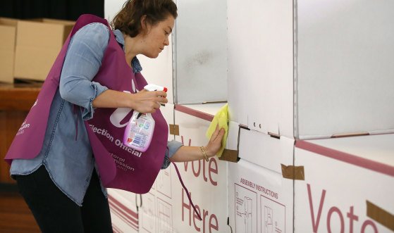 Voting during COVID-19: An election official sanitising a polling booth during the Brisbane council elections in March.