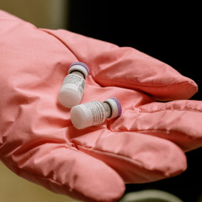 Lynn Peffer, wearing gloves that allow her to handle ultra-cold materials, holds two vials of the Pfizer-BioNTech COVID-19 vaccine in the pharmacy at the Children's Hospital of Pittsburgh. Pfizer reported that about one out of eight vaccine recipients aged 18 to 55 had a bad headache after the first of two doses.  