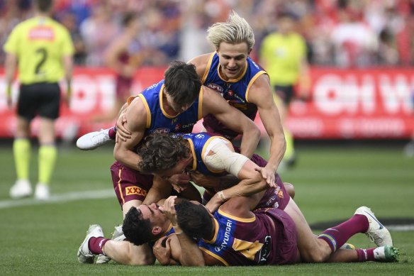 Lions players pile onto each other as they celebrate their AFL premiership victory.