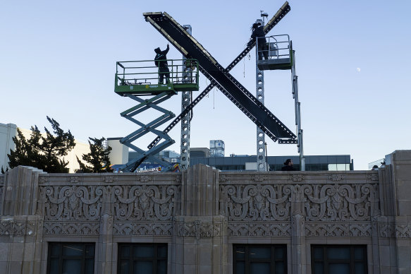 Workers install lighting on an “X” sign atop the downtown San Francisco building that housed what was formally known as Twitter.