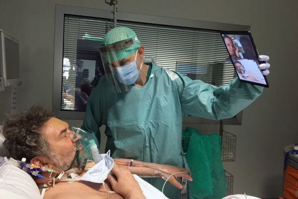 Doctor Matteo Flippini holds a tablet for a patient Alessandro Mattinzoli to talk to his relatives from the intensive care unit of a hospital in Brescia. 