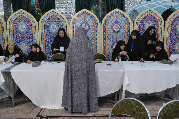 A woman gets her ballot to vote at a polling station at the shrine of Saint Saleh in Tehran.