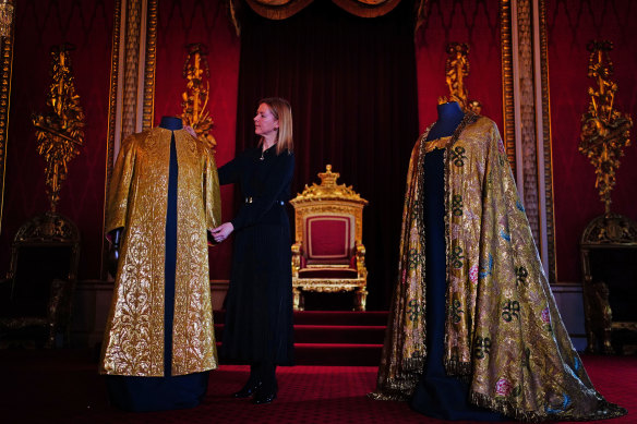 Caroline de Guitaut, deputy surveyor of the King’s Works of Art for the Royal Collection Trust, adjusts the coronation vestments, comprising of the Supertunica (left) and the Imperial Mantle (right), displayed in the Throne Room at Buckingham Palace.