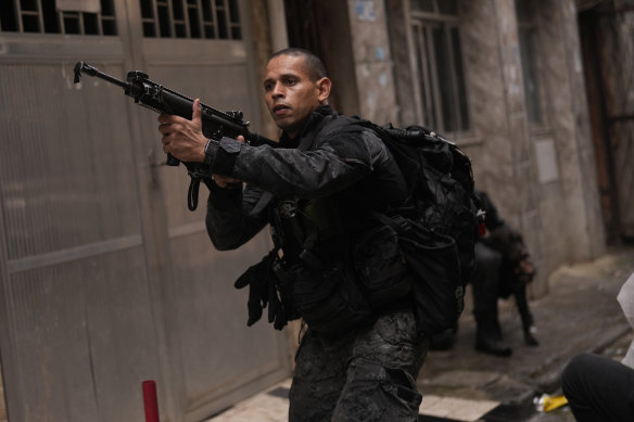 A police officer aims his weapon during a police operation against organised crime in the Mare Complex of Rio de Janeiro on October 9.
