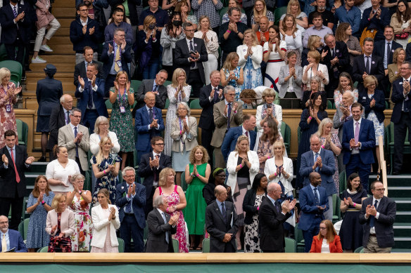 Royals and spectators  stand for Oxford Professor Sarah Gilbert (seated in red, bottom right) on the opening day of Wimbledon. 