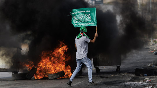 A Palestinian youth carries a Hamas flag amid clashes with Israeli soldiers in the West Bank on October 27.