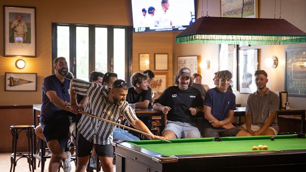 The pool table sits under a fringed lamp.