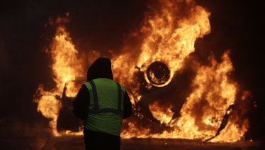 A demonstrator watches a burning car near the Champs-Elysees during a demonstration on Saturday.