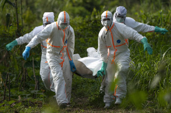 Burial workers in protective gear carry the remains of someone that died of Ebola in Beni, Congo in 2019.