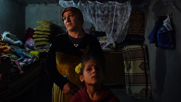 Sehla (left) complains that the roof of her hut leaks as she plaits her daughters hair in Basirma refugee camp, Iraq.