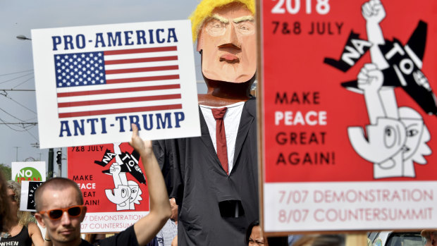 A protester marches next to giant puppet of US President Donald Trump as he holds a sign which reads 'Pro-America, Anti-Trump' during a demonstration in Brussels on Saturday.