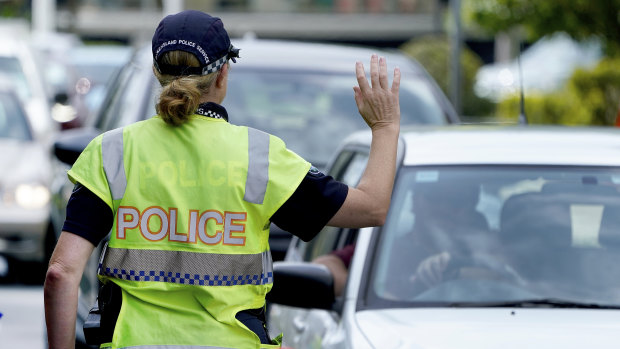 A police officer stops a driver at a checkpoint at Coolangatta on the Queensland - New South Wales border on Thursday.