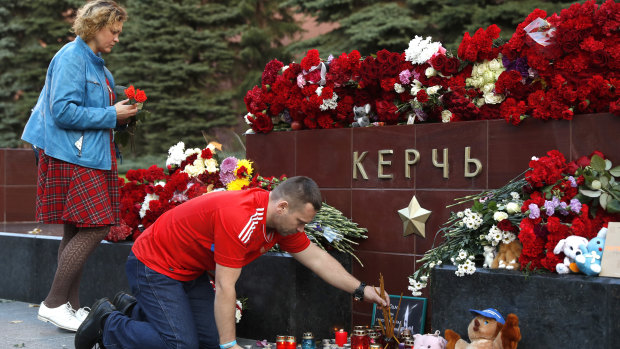 People bring flowers and candles to honor the victims of Wednesday's attack on a vocational college in Kerch, Crimea.