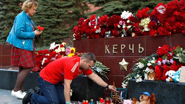 People bring flowers and candles to honor the victims of Wednesday's attack on a vocational college in Kerch, Crimea.